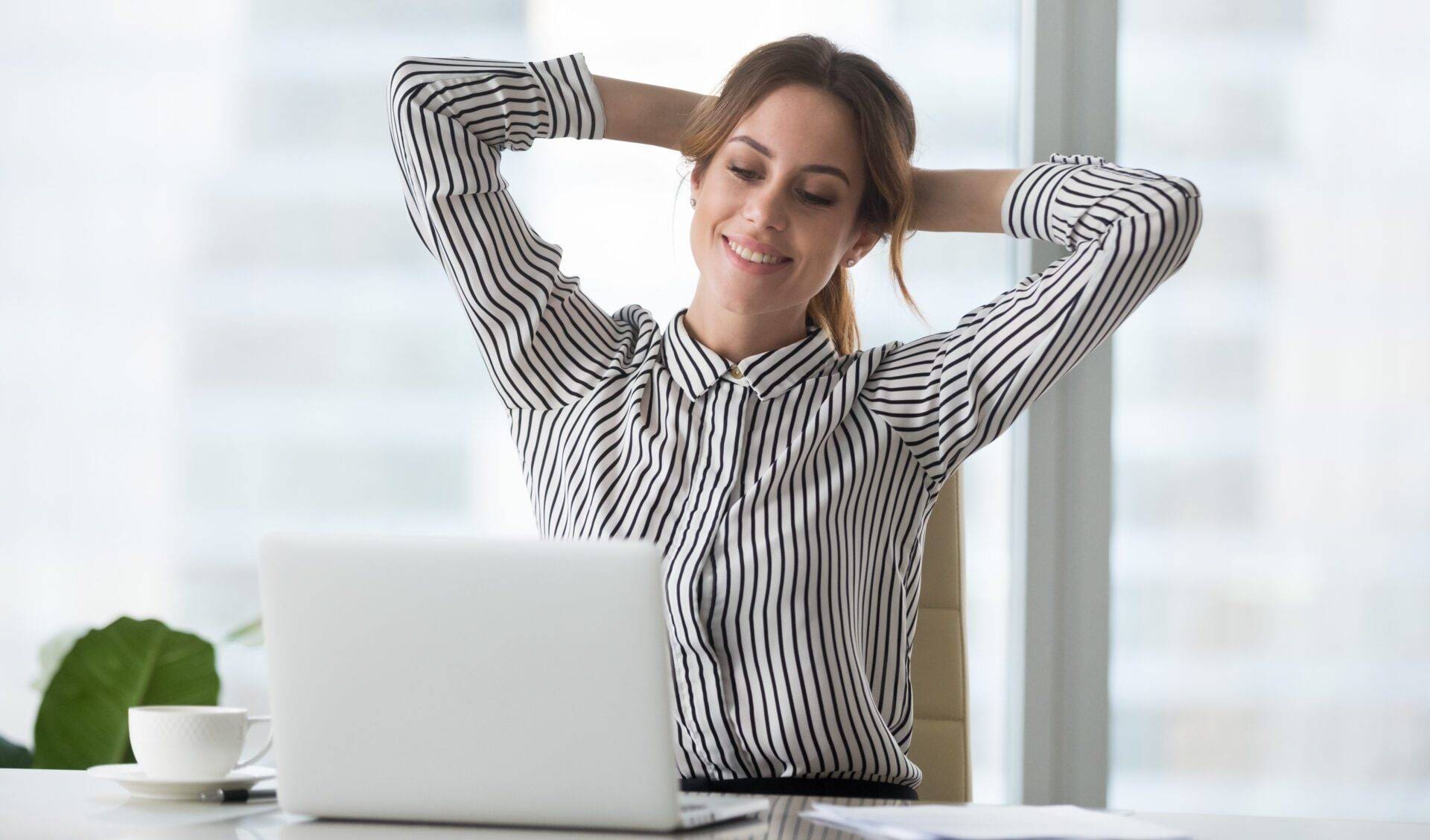 Satisfied woman relaxing with hands over head.