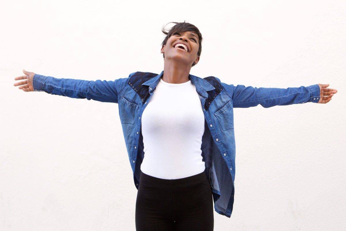 Portrait of a carefree young woman standing with arms spread open